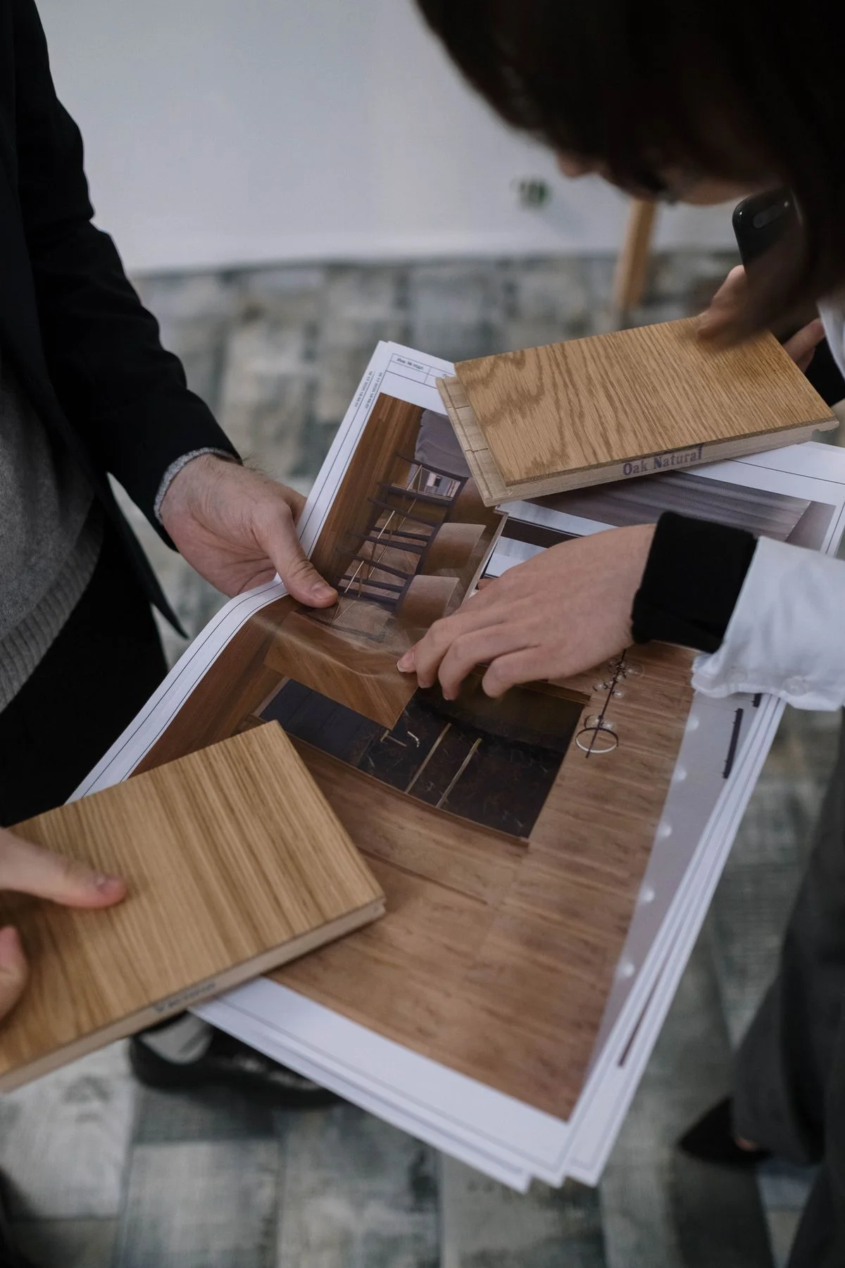 People comparing timber samples with an interior drawing.