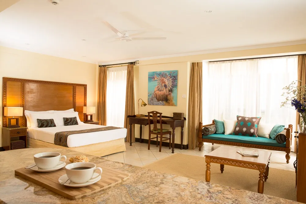 Suite with a bed and adjoining seating area — Heron Portico Hotel