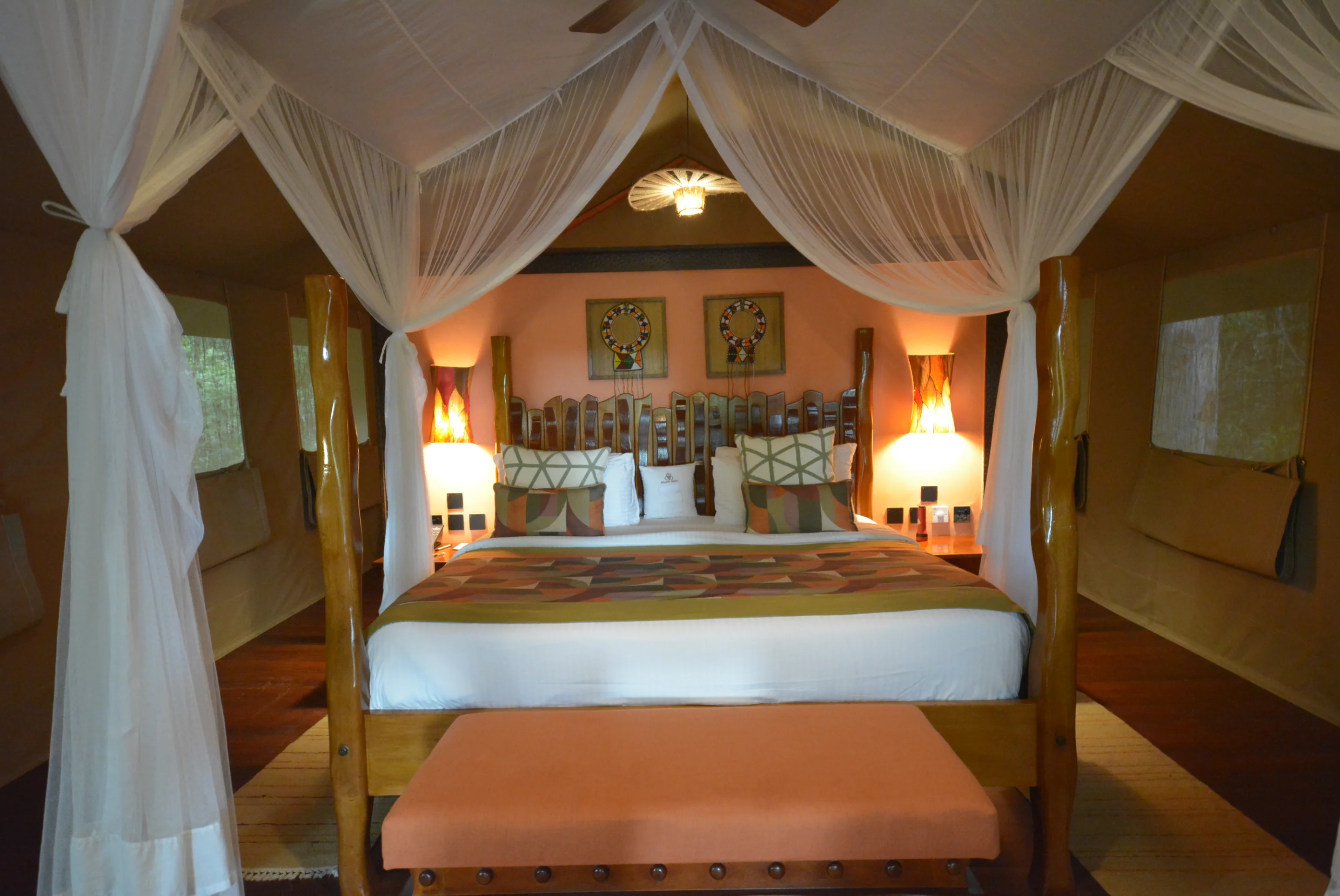 Sarova Mara Club Tent bedroom with a draped canopy, carved headboard and patterned textiles