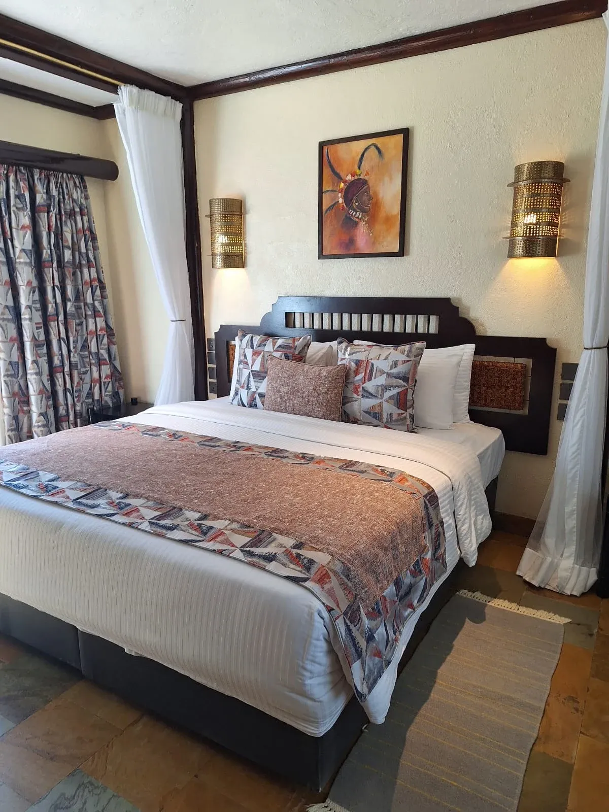 Sarova Shaba West Wing bedroom with an upholstered bed and patterned curtains