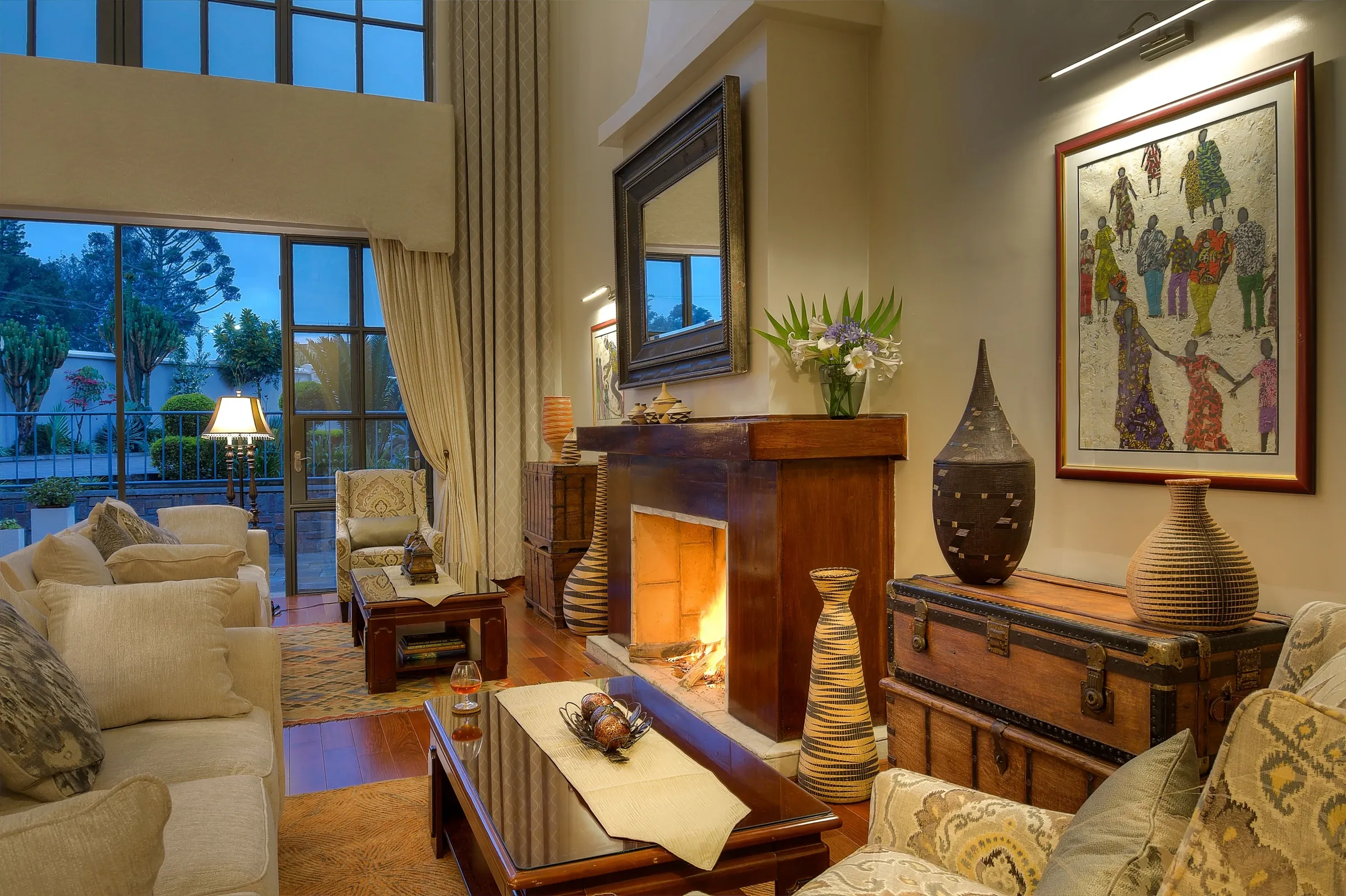 The Bishops House lounge with a fireplace, upholstered seating and doors opening toward greenery