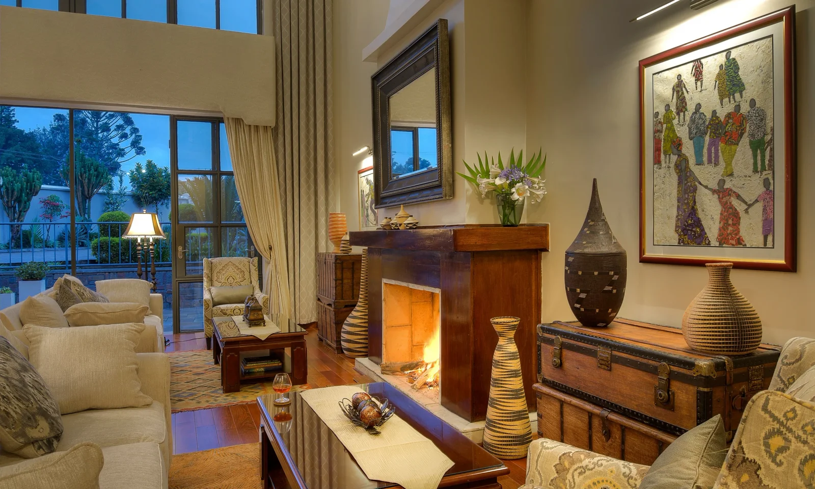 The Bishops House lounge with a fireplace, upholstered seating and doors opening toward greenery