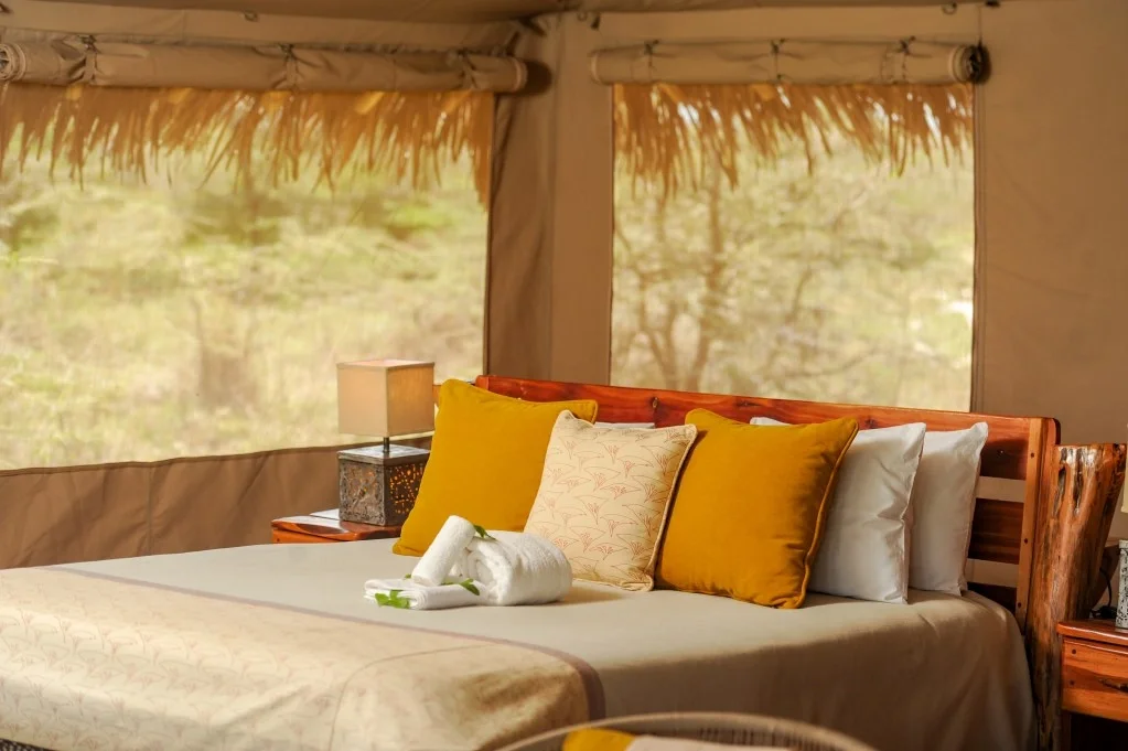 Guest bedroom at Mara Siana with a timber bed, patterned cushions and a bedside lamp