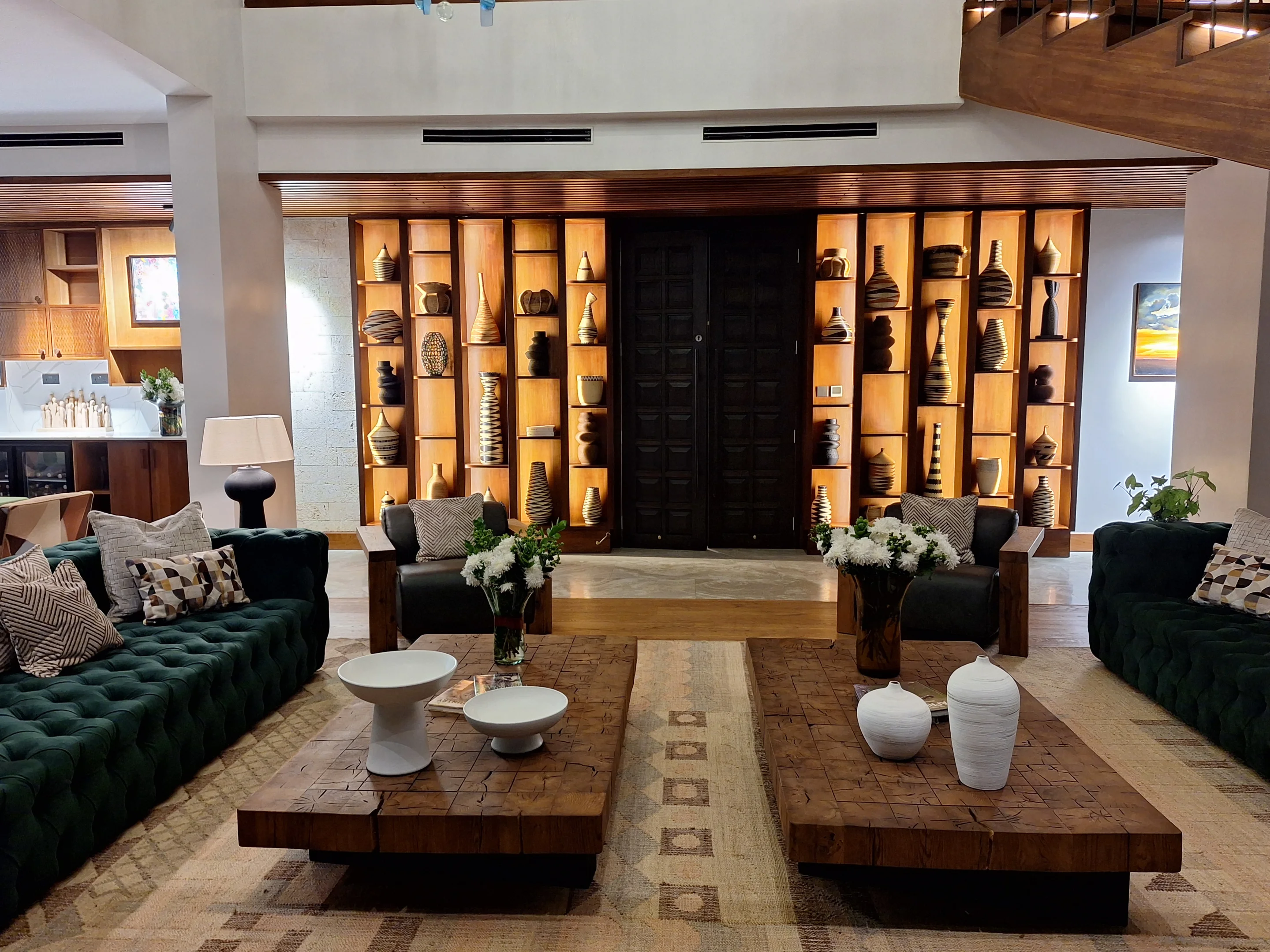 Sky Villa Soleil lounge with teal sofas, carved timber tables and illuminated display shelves