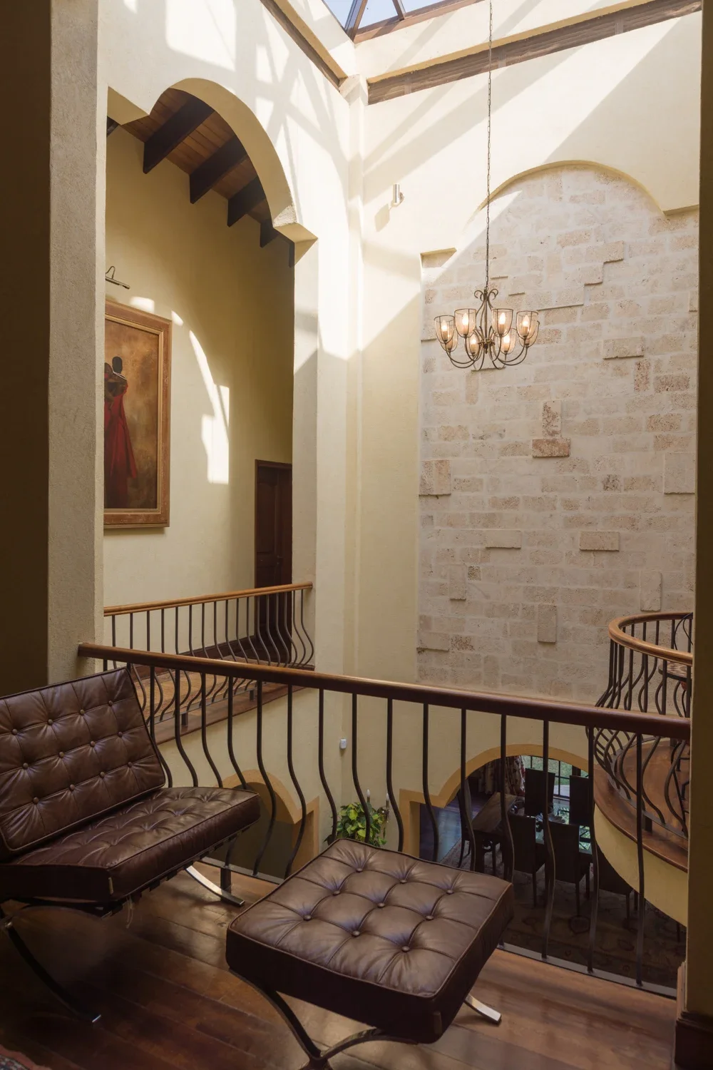 Tall residential atrium with a chandelier, patterned seating and a curved balustrade