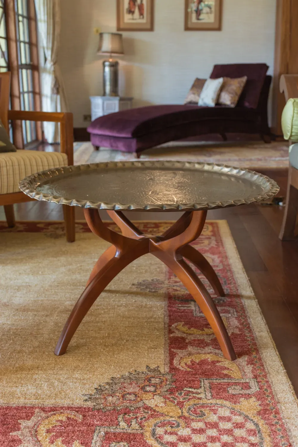 Carved timber side table beside a patterned rug in Mbogani