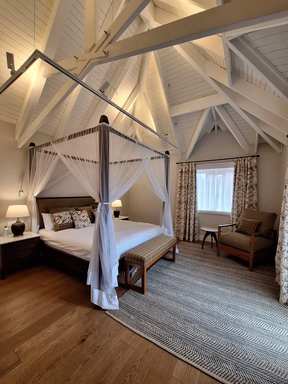 Bedroom with a draped four-poster bed beneath a vaulted timber ceiling
