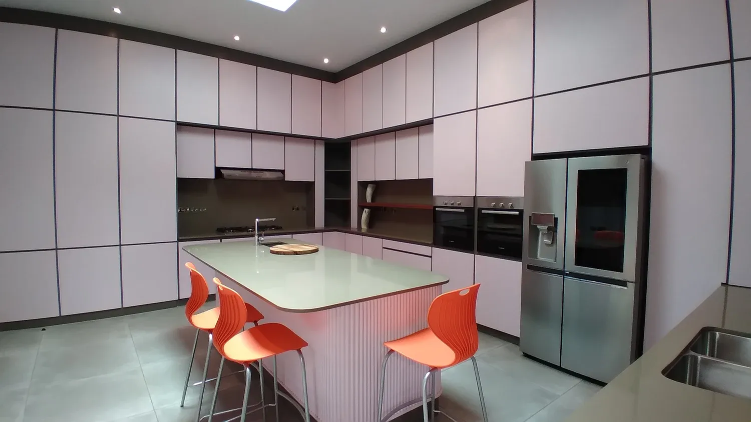 Fitted kitchen with a central island, orange stools and full-height cabinetry