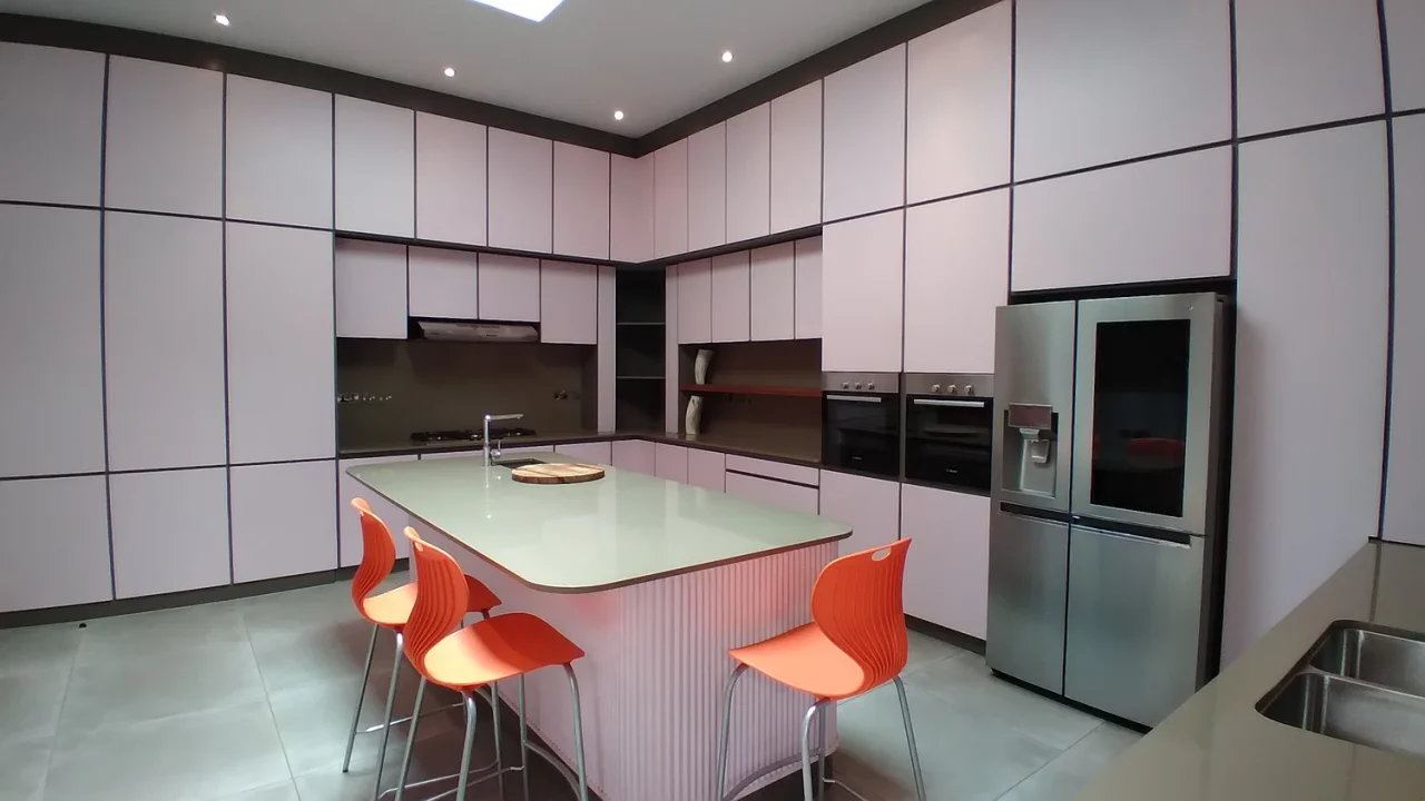 Fitted kitchen with a central island, orange stools and full-height cabinetry