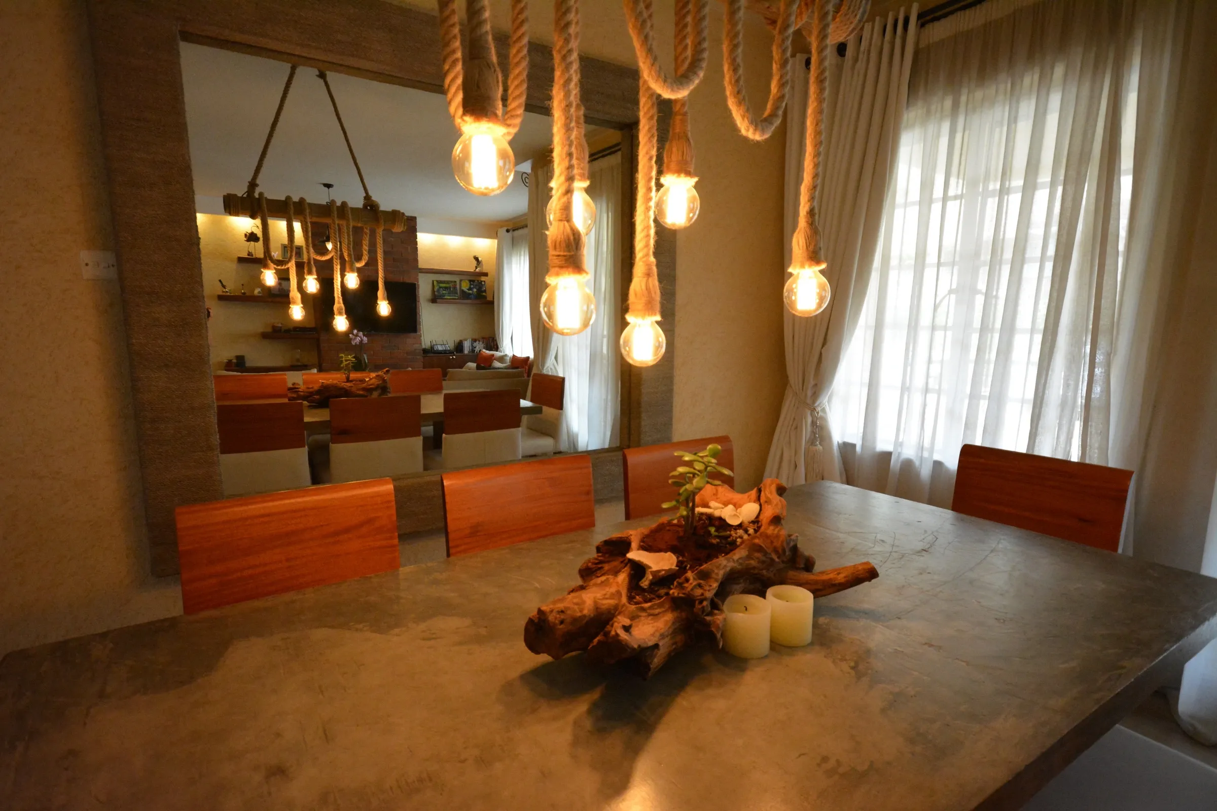 Westlands dining area with a concrete table, timber chairs and suspended rope pendant lights